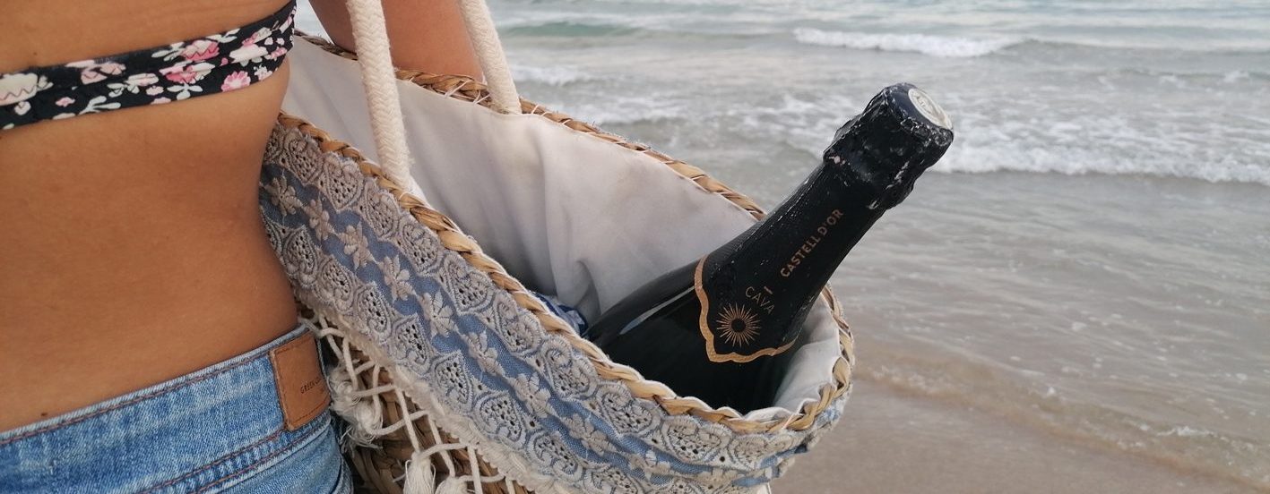 Noia amb ampolla de Cava a la platja