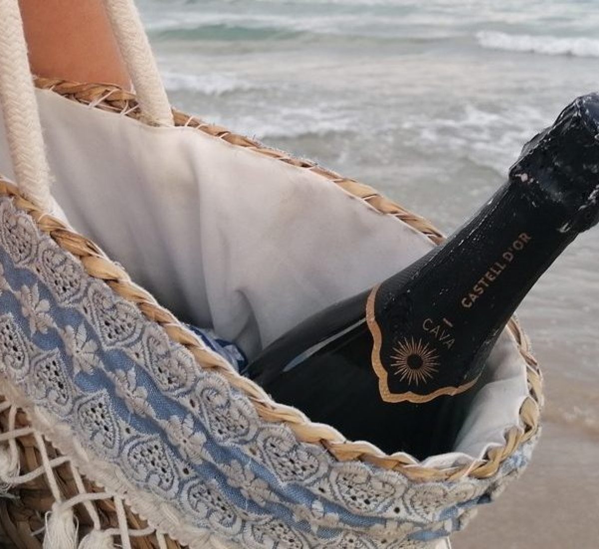 Noia amb ampolla de Cava a la platja